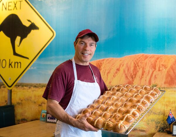 Neville Steel, a baker and co-owner at Australian Bakery Cafe, holds a fresh batch of hot cross buns. CONTRIBUTED BY HENRI HOLLIS