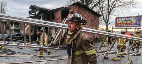 An Atlanta firefighter brings back a ladder at a fire at an apartment building on Joseph E. Boone Boulevard that left one person dead on March 29, 2022. (John Spink / John.Spink@ajc.com)