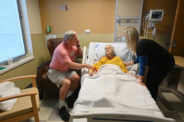 Bill Collins holds the hand of his mother, Edith Collins, as Candice Wade (right), a registered nurse, checks on her at the cardiovascular unit of the Northeast Georgia Medical Center in Gainesville. With the number of coronavirus cases falling dramatically, hospitals are opening back up to visitors. (Hyosub Shin / Hyosub.Shin@ajc.com)