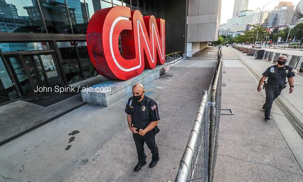 Atlanta police walk by the CNN sign early Monday. The sign, which is a popular tourist photo spot, was damaged by vandals during protests Friday in downtown Atlanta.