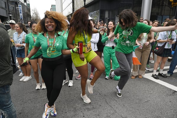 Spectators dance as the floats head down Peachtree Street during the Atlanta St. Patrick's Parade, Saturday, March 15, 2025, in Atlanta. The parade begins at noon at the corner of 15th and Peachtree streets and will continue south along Peachtree to 5th Street. Everyone is encouraged to be Irish for the day as they watch the parade, which is filled with floats, bands, bagpipe and drum corps, dancers, clowns, drill teams and more. (Hyosub Shin / AJC)