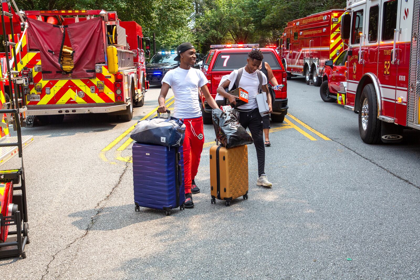 Tremaine Holifield (left) and Rmgud Allen, who were staying at the Arrive Perimeter apartment complex in Dunwoody, head out with their packed bags after an explosion damaged their building Sunday.