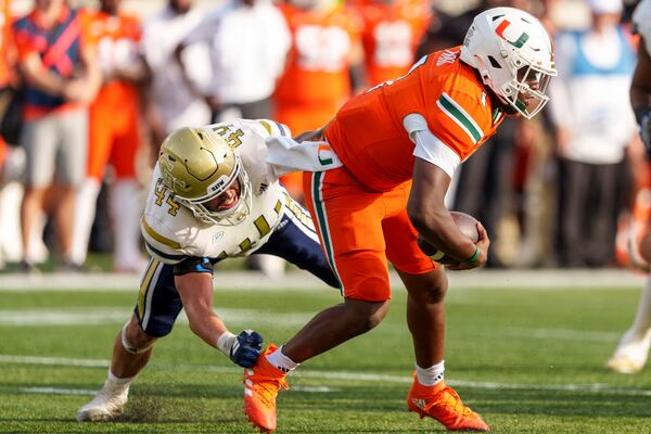 Miami quarterback Cam Ward, right, is nearly sacked by Georgia Tech linebacker Kyle Efford, left, during the second half of an NCAA college football game, Saturday, Nov. 9, 2024, in Atlanta. (AP Photo/Jason Allen)