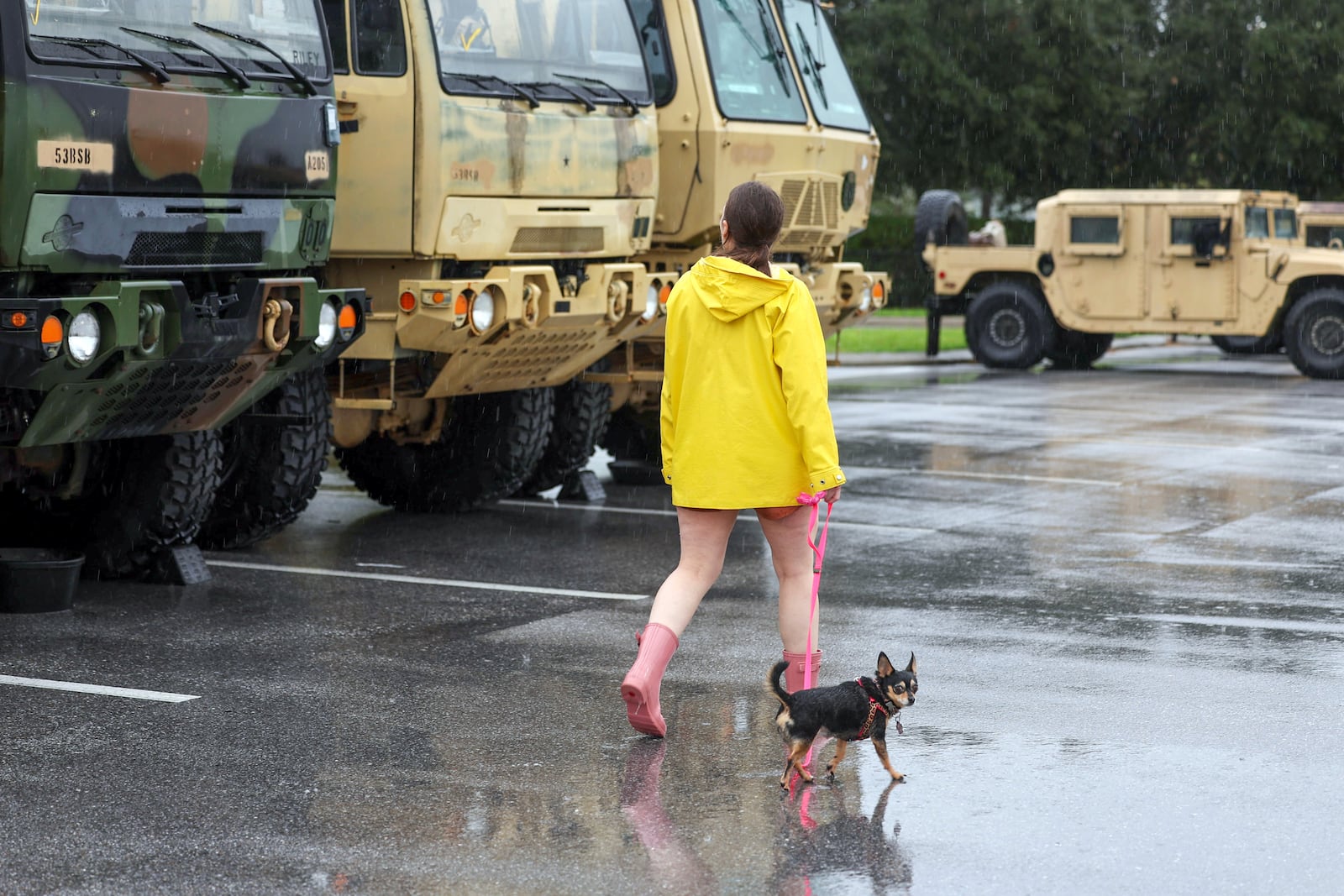 Erin Ferguson walks her dog while looking at equipment stationed by the Florida National Guard in preparation for Hurricane Milton, Wednesday, Oct. 9, 2024, in New Port Richey, Fla. (AP Photo/Mike Carlson)