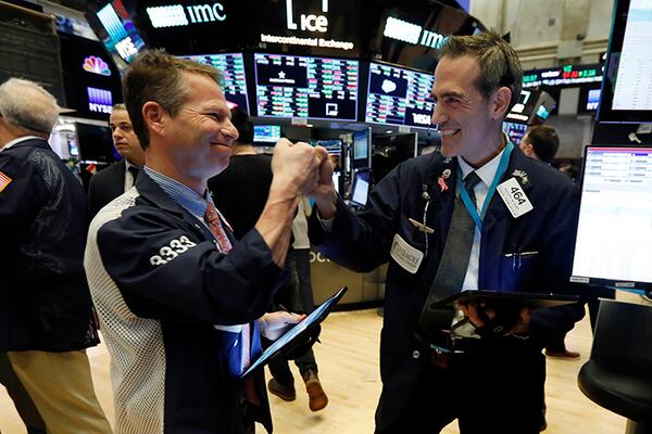 Traders Robert Charmak, left, and Gregory Rowe fist bump at the close of trading, on the floor of the New York Stock Exchange, Monday, March 2, 2020.