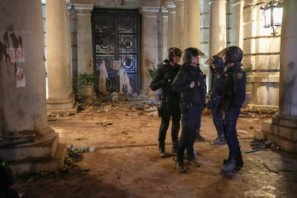 Riot police stand next to a government building littered by some demonstrators during minor clashes after a peaceful protest organized by social and civic groups, denouncing the handling of recent flooding under the slogan "Mazon, Resign," aimed at the president of the regional government Carlos Mazon, in Valencia, Spain, Saturday, Nov. 9, 2024. (AP Photo/Emilio Morenatti)