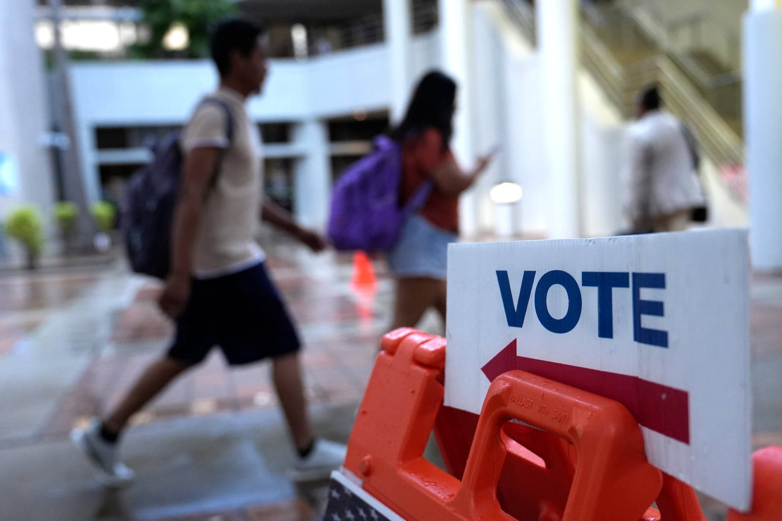 People walk past a Vote sign on the first day of early voting in the general election, Oct. 21, 2024, in Miami. (AP Photo/Lynne Sladky, File)