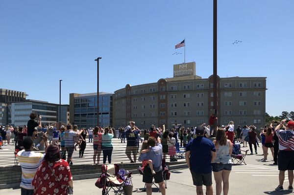 Crowds watch the U.S. Navy Blue Angels and Air Force Thunderbirds pass over Northside Hospital in Sandy Springs on Saturday in a flight honoring health workers caring for COVID-19 patients. J. Scott Trubey/strubey@ajc.com