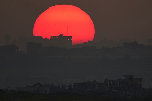 The sun sets behind the buildings that were destroyed during the Israeli air and ground offensive in the Gaza Strip as seen from southern Israel, Monday, March 10, 2025. (AP Photo/Leo Correa)