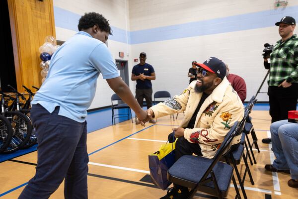 Matthew Robinson, 12, shakes hands with rapper Big Boi of Outkast during a bike giveaway at KIPP WAYS Academy middle school in Atlanta.  (Arvin Temkar / AJC)