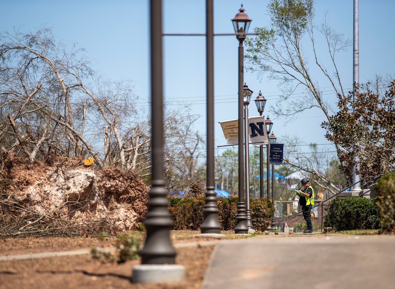 A workman surveys damage to uprooted trees at Newnan High School. (Alyssa Pointer / Alyssa.Pointer@ajc.com)