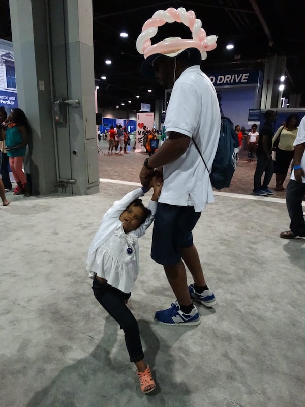 Robert Delaney and his four-year-old daughter Alani enjoy the music by the Ford stage. CREDIT: Rodney Ho/ rho@ajc.com