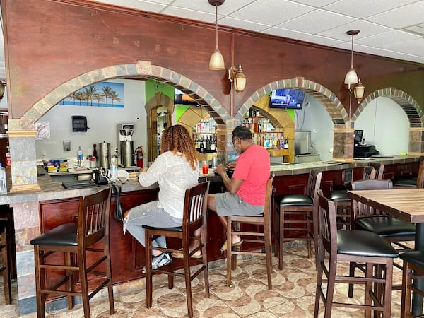 Customers enjoy a meal at the bar at Spicy Hill, a new Jamaican restaurant in Jonesboro. Wendell Brock for The Atlanta Journal-Constitution