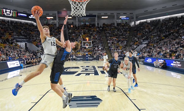 Utah State guard Mason Falslev (12) shoots as Air Force forward Luke Kearney, second from left, defends in the first half of an NCAA college basketball game Saturday, March 8, 2025, in Logan, Utah. (Eli Lucero/The Herald Journal via AP)