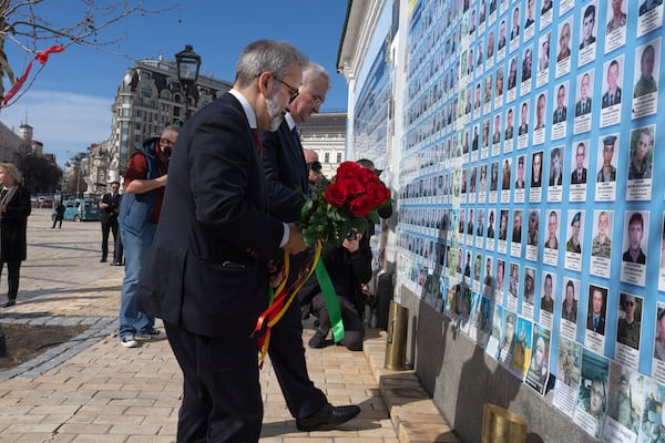 Portugal's foreign Minister Paulo Rangel, front and Ukraine's Foreign Minister Andrii Sybiha, behind, lay flowers at the memorial wall of the fallen soldiers in Kyiv, Ukraine, Friday, March 14, 2025. (AP Photo/Efrem Lukatsky)