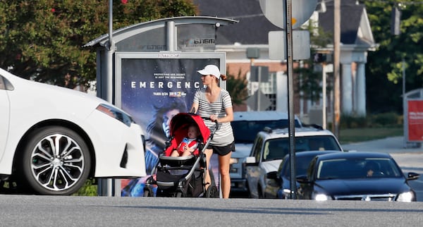 A pedestrian waits to cross the Mt. Vernon and Chamblee Dunwoody Road intersection in Dunwoody. The city recently passed a “Vulnerable Road User” ordinance. (Photo: Bob Andres / robert.andres@ajc.com)