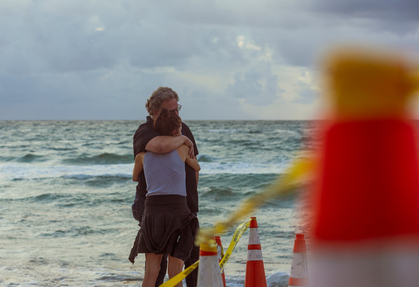 Onlookers embrace on the beach near the partially collapsed 12-story Champlain Towers South condo building in Surfside, Fla., Friday morning June 25, 2021. (Saul Martinez/The New York Times)