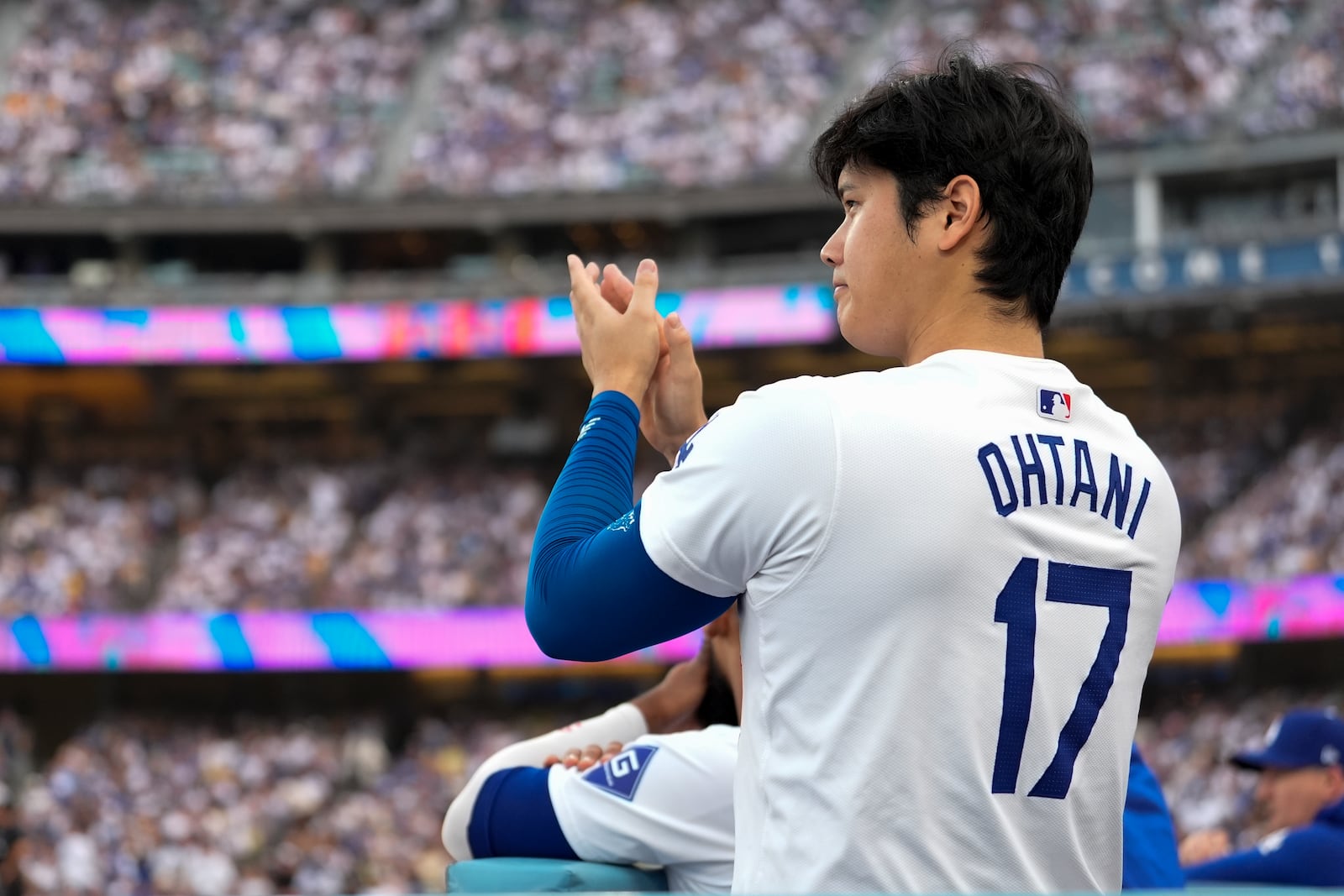 Los Angeles Dodgers' Shohei Ohtani applauds in the dugout during the second inning in Game 5 of a baseball NL Division Series against the San Diego Padres, Friday, Oct. 11, 2024, in Los Angeles. (AP Photo/Ashley Landis)