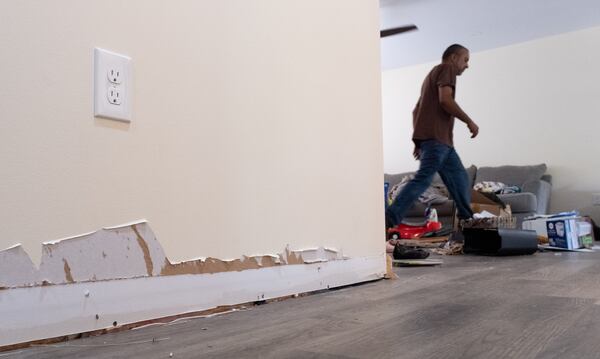 Rajesh Desor tries to organize belongings after a sewage backup forced his family from their Stone Mountain rental home. The family was forced to pay more than $5,200 for hotels and Airbnbs, their receipts show. Desor's wife Mary McElya says, “We’re covered for nothing. No one has even cared.” (Ben Gray / Ben@BenGray.com)