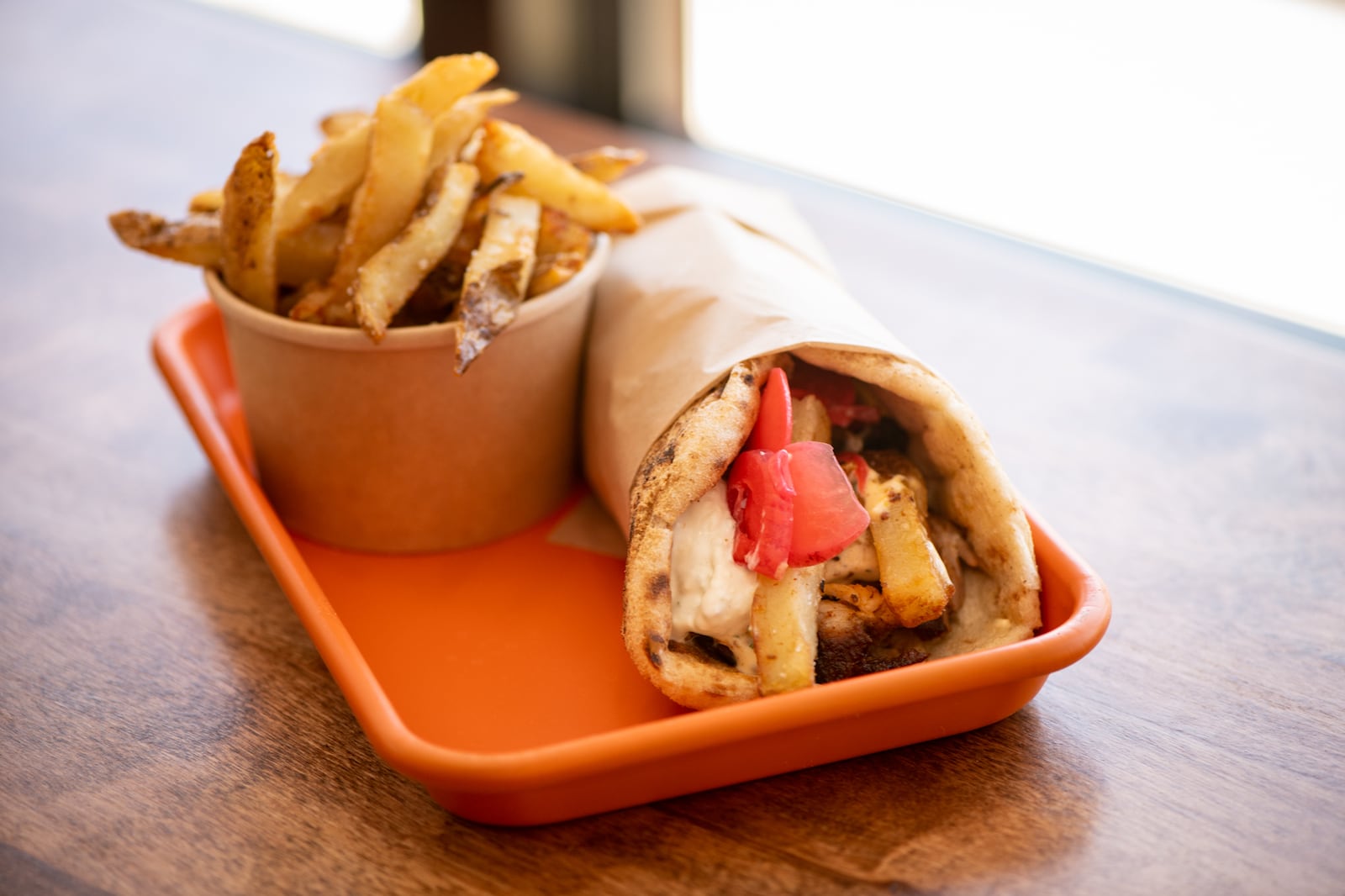 Karv Kitchen Greko wrap with pork souvla, tangy mustard, tomato, spicy tzatziki, pickled red onion, and radish, served with KRAV fries. (Mia Yakel for The Atlanta Journal-Constitution)