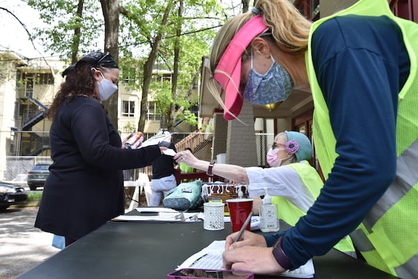 In this file photo, volunteers Jodi Lewis Lipsitz and Stefanie Agusta (right) help a client with checking in for COVID-19 vaccination at the parking lot of Highland Urgent Care & Family Medicine in Atlanta. (Hyosub Shin / Hyosub.Shin@ajc.com)