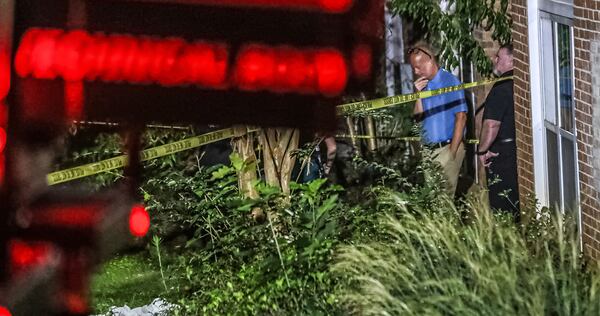 Sgt. Lynn Shuler (left) surveys a grassy area outside a breezeway where a man in his mid-20s was found shot multiple times Thursday morning at the Oak Forest Apartments in Scottdale.