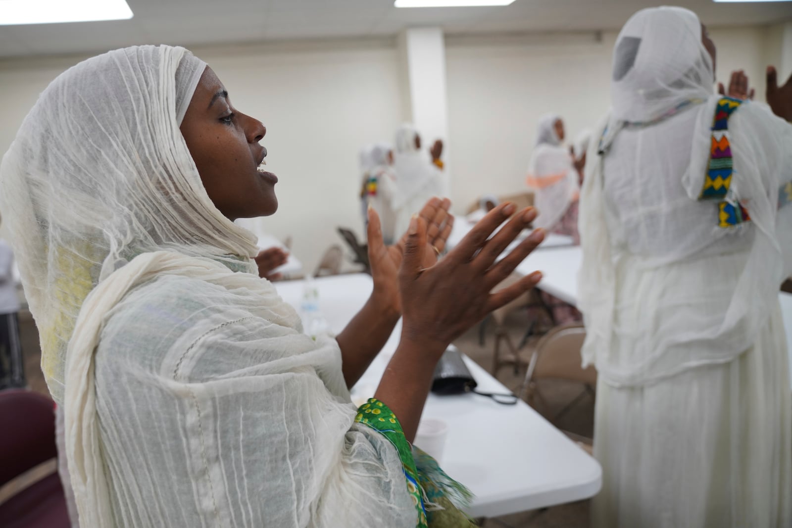 Mintamir Endanew, left, and other members of the Ethiopian Orthodox Tewahedo Church pray after a post-liturgy lunch of pancake-like injera bread on Sunday, Oct. 20, 2024, in Worthington, Minn. (AP Photo/Jessie Wardarski)