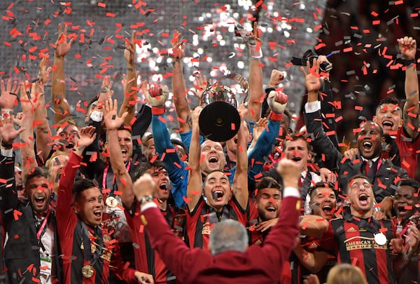 Atlanta United midfielder Miguel Almiron (center) raises the MLS Cup as they celebrate after their 2-0 win over the Portland Timbers during the 2018 MLS Cup at Mercedes-Benz Stadium on Saturday, December 8, 2018. HYOSUB SHIN / HSHIN@AJC.COM