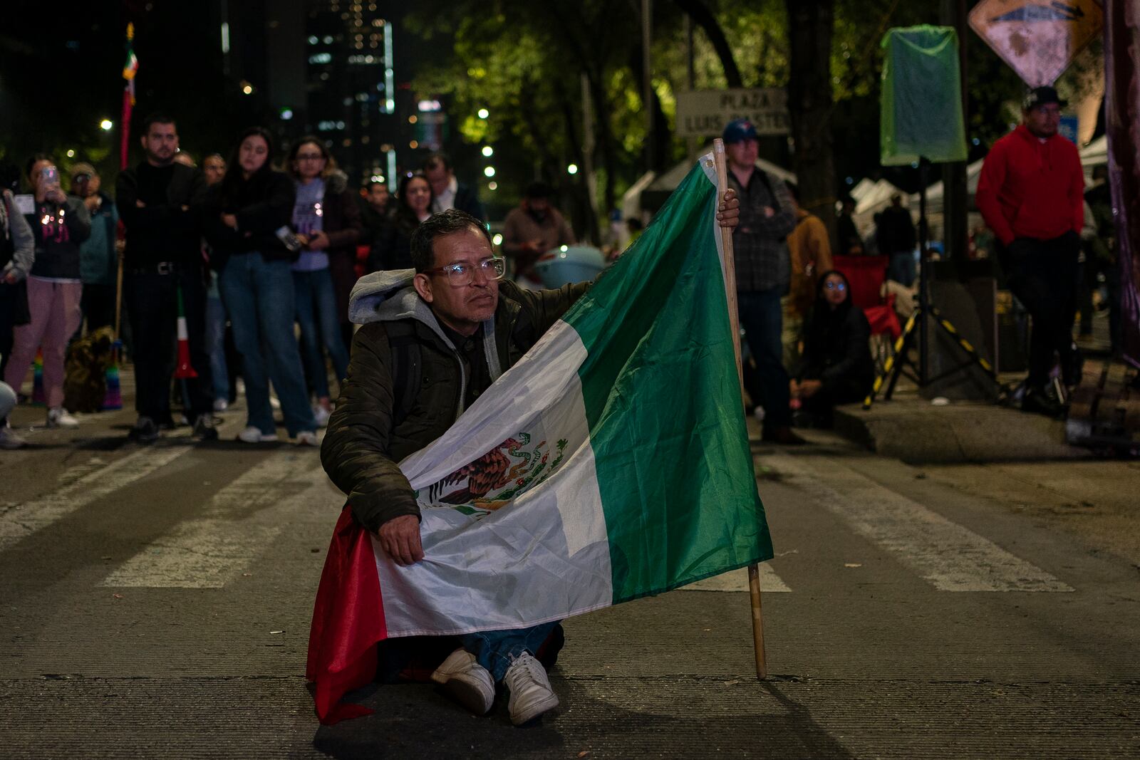 A man carrying a Mexican flag watches the senators' vote on a large screen during a protest against government's proposed judicial reform, which would make judges stand for election, outside the Senate in Mexico City, Tuesday, Sept. 10, 2024. (AP Photo/Felix Marquez)