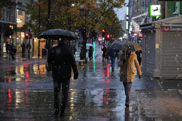 People walk along the Oxford Street as snow falls in London, Tuesday, Nov. 19, 2024. (AP Photo/Kin Cheung)