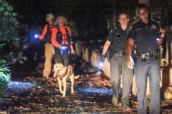 Investigators used police dogs in the search and conducted door-to-door checks. JOHN SPINK / JSPINK@AJC.COM