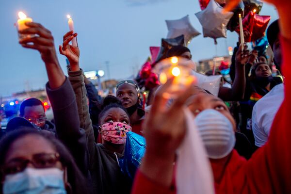 Family and friends lift their candles to the sky and release balloons to honor Calvin Munerlyn during a vigil Sunday.