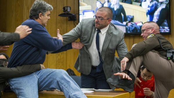 Randall Margraves, father of three victims of Larry Nassar , left, lunges at Nassar, bottom right, Friday, Feb. 2, 2018, in Eaton County Circuit Court in Charlotte, Mich.  The incident came during the third and final sentencing hearing for Nassar on sexual abuse charges. The charges in this case focus on his work with Twistars, an elite Michigan gymnastics club.   (Cory Morse/The Grand Rapids Press via AP)