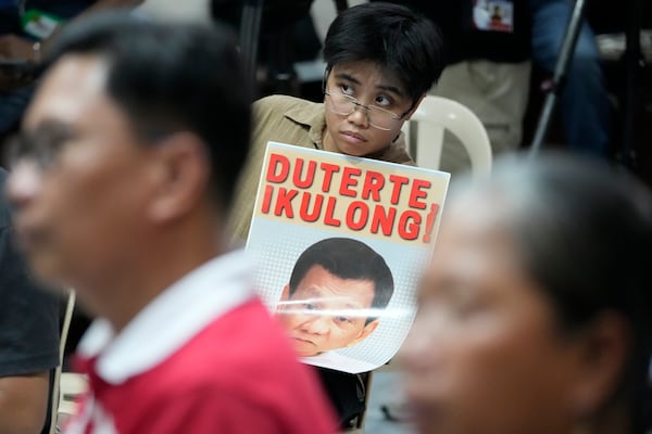 An activist holds a slogan as they watch a broadcast of the first appearance at the International Criminal Court (ICC) of former President Rodrigo Duterte in Quezon city, Philippines on Friday, March 14, 2025. (AP Photo/Aaron Favila)