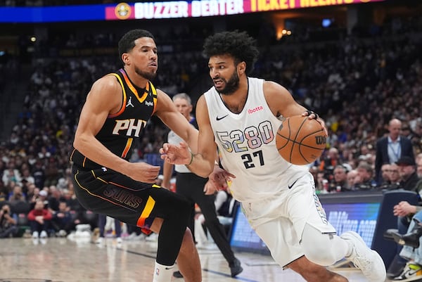 Denver Nuggets guard Jamal Murray, right, drives to the basket past Phoenix Suns guard Devin Booker in the first half of an NBA basketball game Friday, March 7, 2025, in Denver. (AP Photo/David Zalubowski)