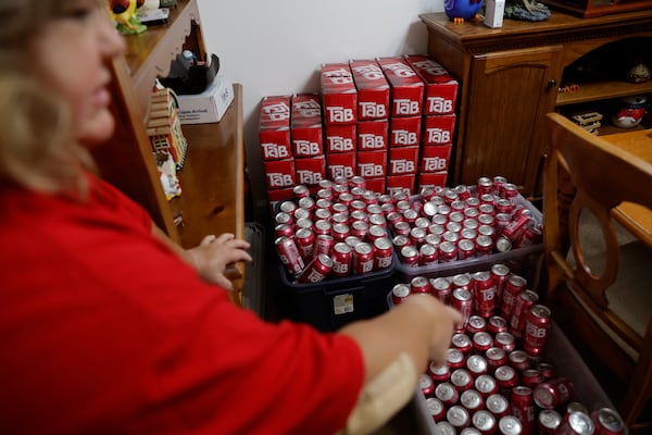 Andrea Ybarbo points to her stash of Tab soda at her home in Mableton on Tuesday, Nov. 21, 2023. Since Coca Cola announced they were discontinuing the diet drink in 2020, Ybarbo went on a search to amass as many cans as possible before they dissipated from the shelves.  (Natrice Miller/ Natrice.miller@ajc.com)