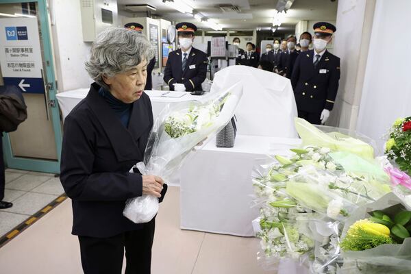 Shizue Takahashi, the wife of a subway worker killed in the March 20, 1995 sarin gas attack, lays flowers on the stand set up at Kasumigaseki subway station in Tokyo Thursday, March 20, 2025. (Japan Pool/Kyodo News via AP)