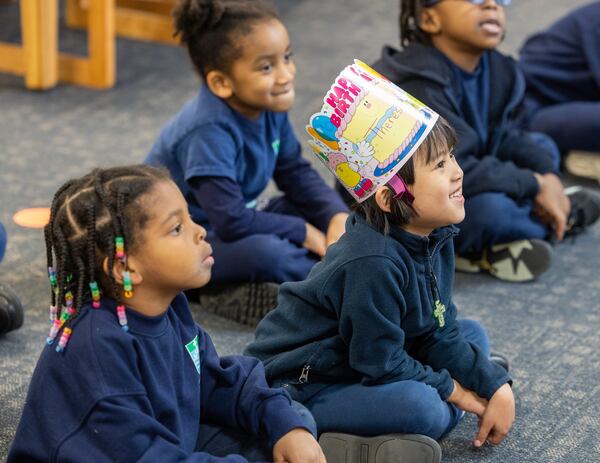 Theresa Lee (birthday hat) laughs as she listens to a volunteer read a book to a group of pre-K and kindergarten students in the Saint Peter Claver Regional Catholic School library. PHIL SKINNER FOR THE ATLANTA JOURNAL-CONSTITUTION