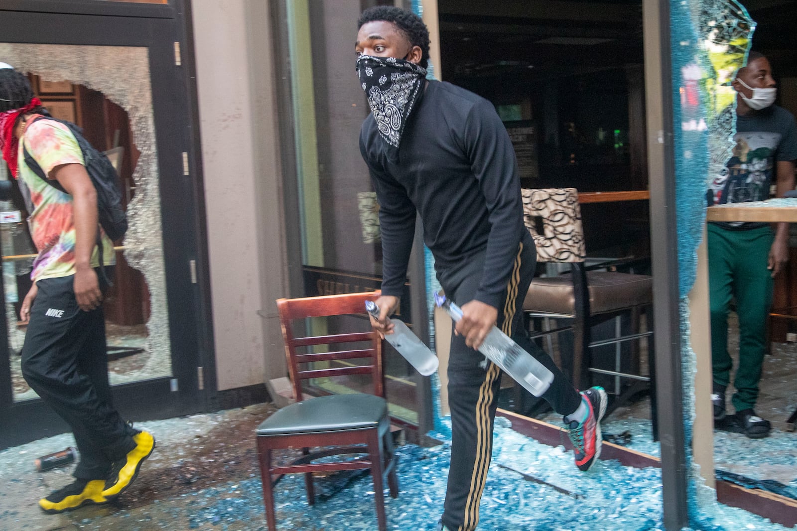 05/29/2020 - Atlanta, Georgia  - A protestor steals bottles of alcohol from McCormick & Schmick's Seafood Restaurant located in the CNN Center after a peaceful protest march turned into rioting and looting in Atlanta, Friday, May 29, 2020. (ALYSSA POINTER / ALYSSA.POINTER@AJC.COM)