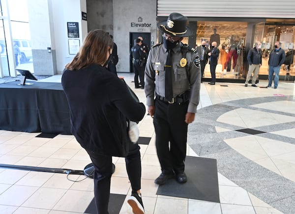 Kenyonn Wallace, security with the mall, inspects a bag after metal detector alarmed at Lenox Square on Tuesday, December 29, 2020. (Hyosub Shin / Hyosub.Shin@ajc.com)