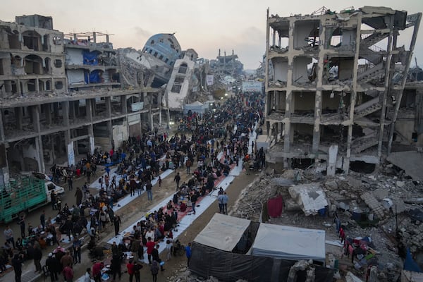 Surrounded by destroyed homes and buildings, Palestinians gather for iftar, the fast-breaking meal during Ramadan in Beit Lahia, northern Gaza Strip, Saturday, March 15, 2025. (AP Photo/Jehad Alshrafi)