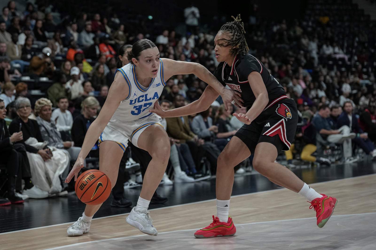 UCLA forward Angela Dugalic, left, dribbles as Louisville guard Imari Berri, right, defends, during an NCAA college basketball game Monday, Nov. 4, 2024, in Paris, France. (AP Photo/Aurelien Morissard)