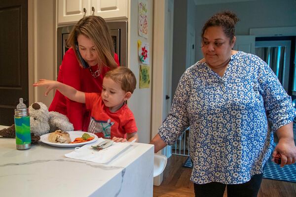 Lyndsey Rudder (left), Republican candidate for state House District 54, is helped by her nanny Olga as they get Maclin, Lyndsey's youngest son, into a seat to eat lunch at her residence in Atlanta on Sept. 14, 2020. Rudder says she is appreciative of the help she receives while navigating this campaign season. (Alyssa Pointer / Alyssa.Pointer@ajc.com)