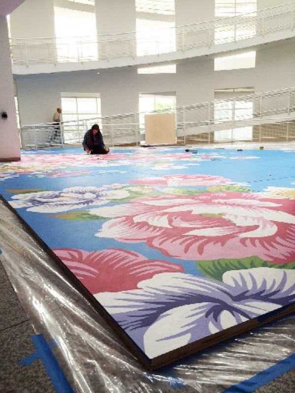 An assisting artist works on Utah Sky 2065-40 (Blue Curve), a monumental, site-specific painting by Shanghai artist Michael Lin on the atrium floor of the Richard Meier-designed High Museum of Art building. The monumental painting goes on view officially beginning April 24 and is one of several exhibits available to High visitors during Museum Week. CONTRIBUTED BY HIGH MUSEUM OF ART