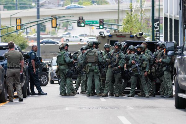 A SWAT team gathers outside a condominium building on 16th and Spring Street in Midtown Atlanta on Monday, August 22, 2022. A woman was arrested at the Atlanta airport a little more than two hours after shots were fired at the building, according to Atlanta police. The woman is suspected of shooting three people. (Arvin Temkar / arvin.temkar@ajc.com)