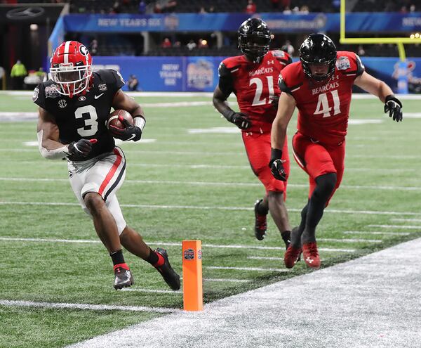 Georgia running back Zamir White gets past Cincinnati defenders Darrian Beavers (from left), Myjai Sanders, and Joel Dublanko for a touchdown during the 4th quarter.   Curtis Compton / Curtis.Compton@ajc.com”