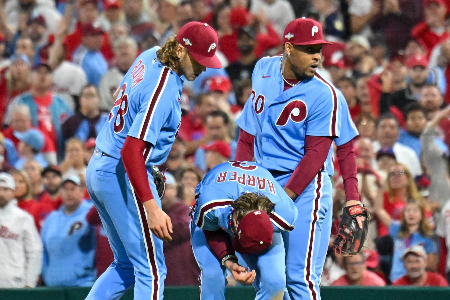 Philadelphia Phillies relief pitcher Gregory Soto (30) and  Alec Bohm (28) check on first baseman Bryce Harper after he collided with Atlanta Braves’ baserunner Matt Olson during the eighth inning of NLDS Game 4 at Citizens Bank Park in Philadelphia on Thursday, Oct. 12, 2023.   (Hyosub Shin / Hyosub.Shin@ajc.com)