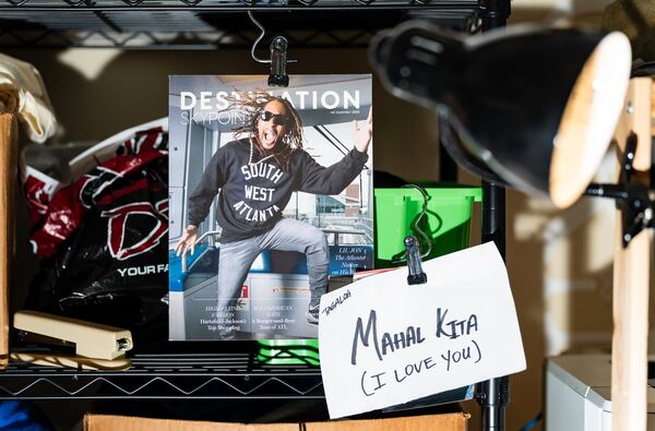 A magazine cover featuring Lil Jon wearing a Cruvie Clothing sweater and a piece of paper with the Tagalog translation of “I love you” hang on a shelving unit at Cruvie Clothing founder Tony Cruver’s home workspace. Cruver, whose mother is Filipino, said he hangs affirmations around his workspace for motivation. (Seeger Gray / AJC)