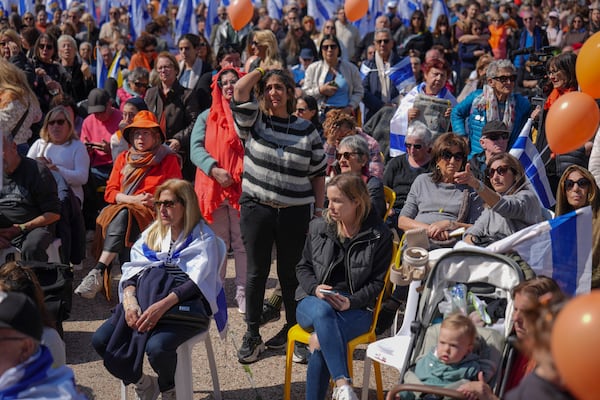 People watch a live broadcast from the funeral of slain hostages Shiri Bibas and her two children, Ariel and Kfir, at a plaza known as the Hostages Square in Tel Aviv, Israel, Wednesday, Feb. 26, 2025. The mother and her two children were abducted by Hamas on Oct. 7, 2023, and their remains were returned from Gaza to Israel last week as part of a ceasefire agreement with Hamas. (AP Photo/Ariel Schalit)