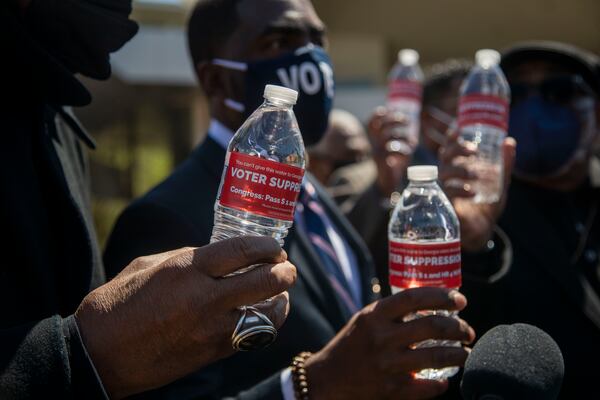 04/01/2021 —Atlanta, Georgia — Religious leaders hold bottles of water with labels that read “Voter Suppression” following a press conference outside of the World of Coca-Cola in downtown Atlanta, Thursday, April 1, 2021. Bishop Reginald T. Jackson has called on people to boycott Coca-Cola, Home Depot and Delta Air Lines because he feels they have not taken a strong stance on SB 202. (Alyssa Pointer / Alyssa.Pointer@ajc.com)